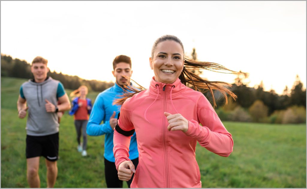 A group of people happily jogging showing the result of holistic care through chiropractic therapy.