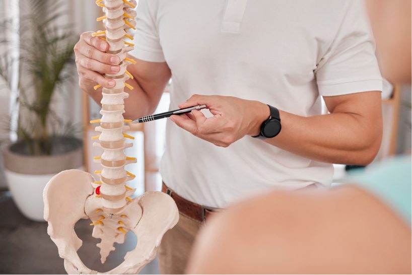 A chiropractor explaining the spinal column condition to a lady patient